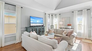 A living room with a large flat-screen TV, a beige sofa, a coffee table, and a decorative lamp.