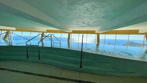 Ein Innenpool mit Infinity-Kante und freiem Blick auf das Meer und das entfernte Umland.