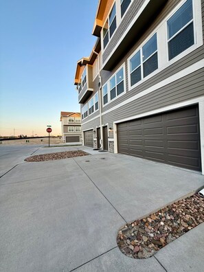 A multi-story residential building with a garage, a stop sign, and a clear sky.