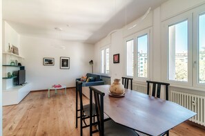 Ein modernes Wohnzimmer mit Esstisch, einer Couch und einem Fernseher.
