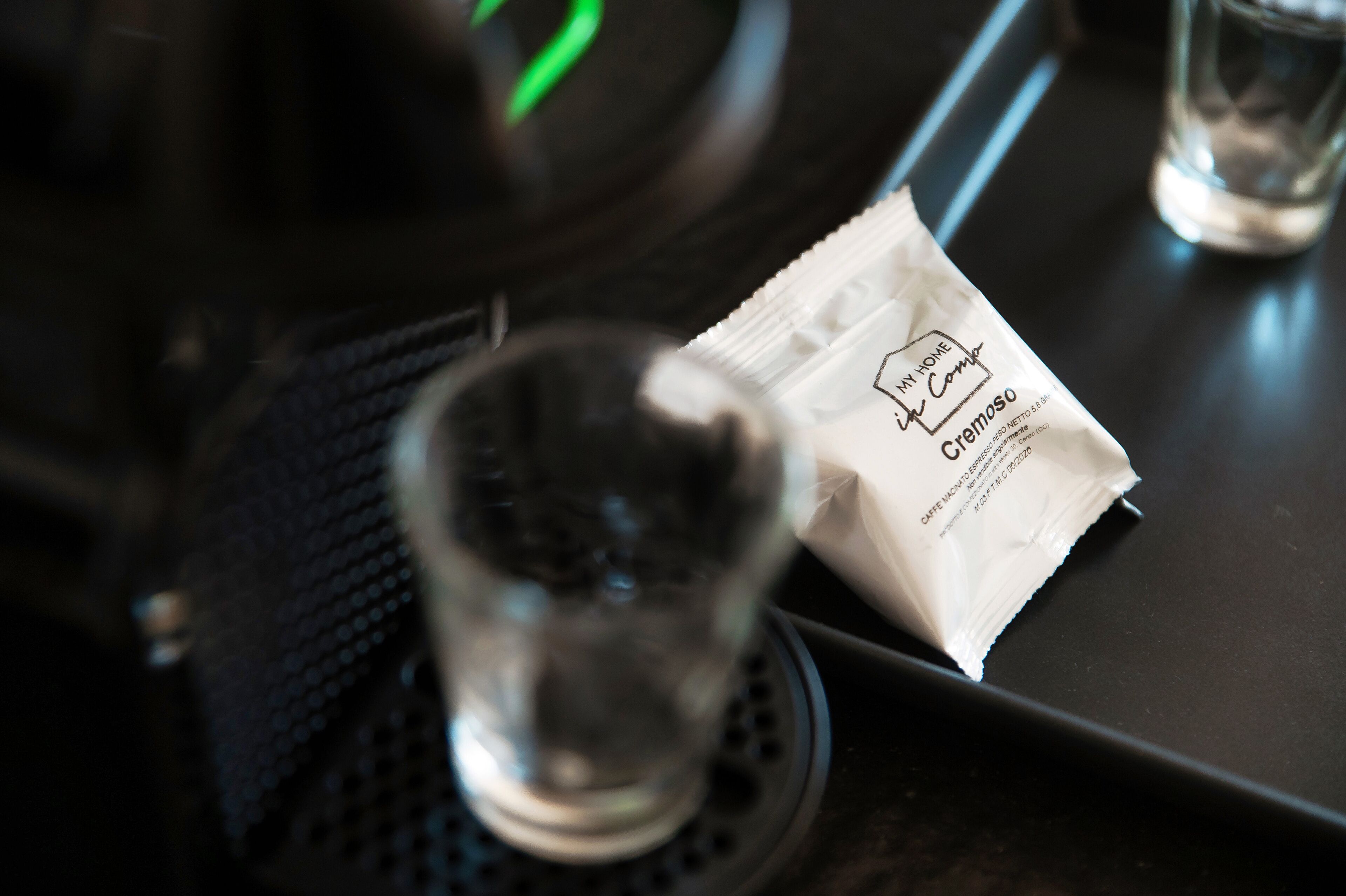 A table with a glass, a packet of cremoso, and a black napkin.