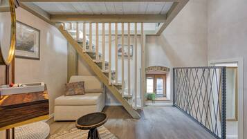 A spacious living area with a wooden staircase, a sofa, a coffee table, and a view of the upper floor.