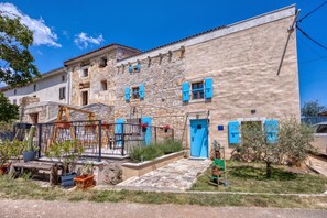 A traditional stone building with a blue door and shutters, surrounded by a garden with potted plants and a metal fence. - Foska Country Home With Private Pool (Svetvincenat)