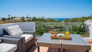 A balcony with wicker furniture, a glass table, and a tray with croissants and orange juice. - 91A Casa Mel: Stylish 3-Bed Townhouse with Pool (Carvoeiro)