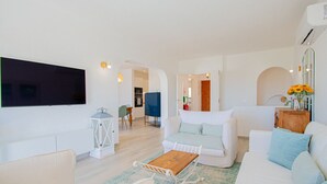 A modern living room with a flat-screen TV, white sofas, a wooden coffee table, and a patterned rug. - 91A Casa Mel: Stylish 3-Bed Townhouse with Pool (Carvoeiro)