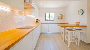 A modern kitchen with white cabinets, a wooden countertop, and a window providing natural light. - 91A Casa Mel: Stylish 3-Bed Townhouse with Pool (Carvoeiro)