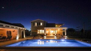 Ein zweistöckiges Haus mit Swimmingpool, Gartenmöbeln und einer überdachten Terrasse.