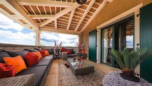 Eine Terrasse im Freien mit einer Couch, Kissen, einem Couchtisch und einem Blumentopf.