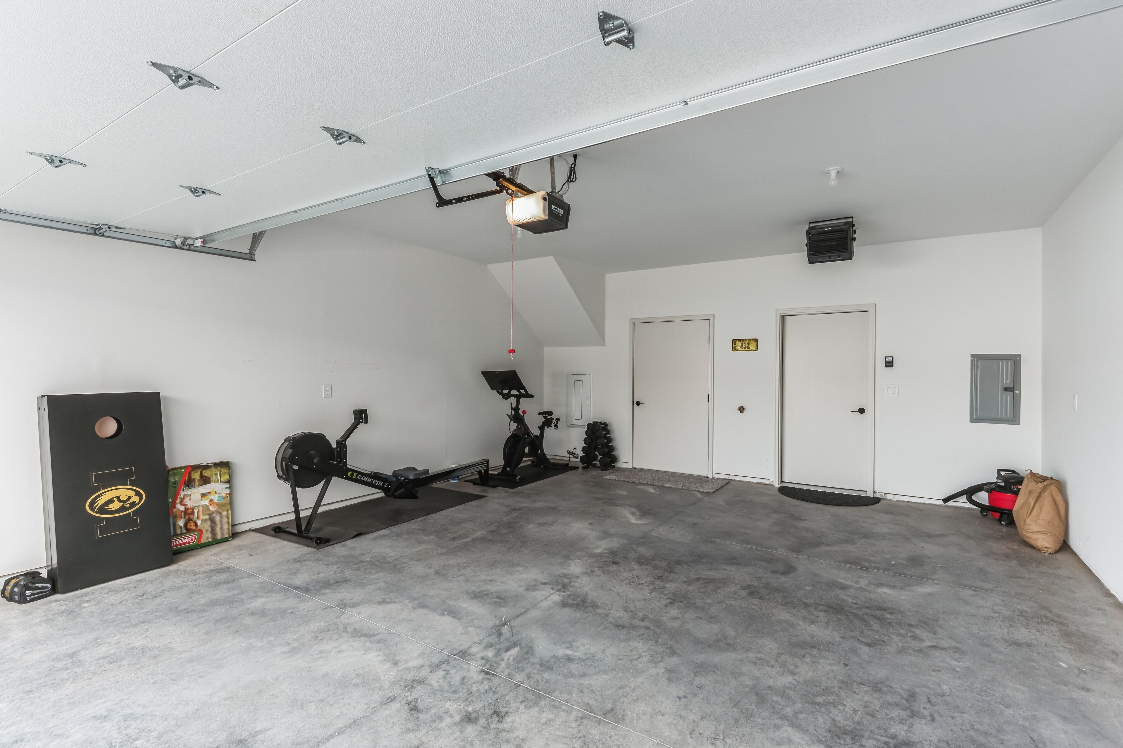 A spacious indoor area with a ceiling-mounted projector, exercise equipment, and a door.