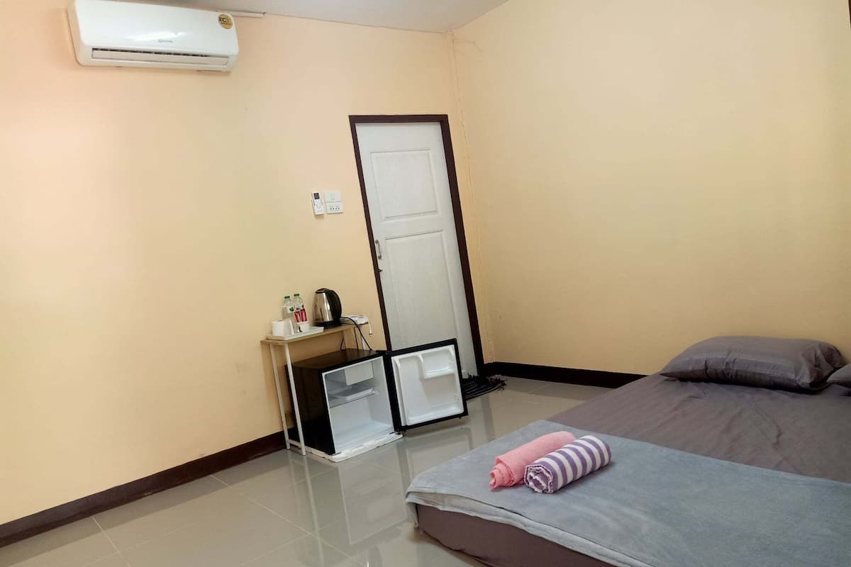 Une chambre d’hôtel équipée d’un lit, d’un bureau avec un ordinateur, d’une bouilloire et d’une bouteille d’eau.