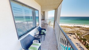 Un balcon avec vue sur la plage, une piscine et un espace salon extérieur.