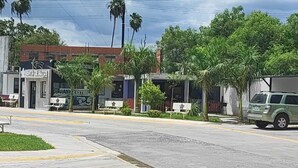 A street view with a car dealership, benches, palm trees, and a building with a sign that reads "RENTA DE AUTOS". - Hotel Estrella Matamoros (Matamoros)