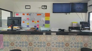 A reception area with a computer, a bulletin board with notes, a television, and a tiled wall. - Hotel Estrella Matamoros (Matamoros)