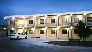 A multi-story motel with a row of rooms, each with a balcony. A white car is parked in front. - Hotel Estrella Matamoros (Matamoros)