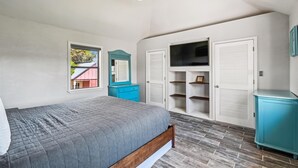 A bedroom with a bed, a wardrobe, a television, and a window with a view of a building outside.