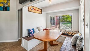 A cozy room with a wooden bench, a table, and a window with blinds.