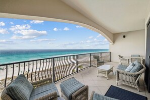 Un balcon doté de meubles en osier, donnant sur une plage.