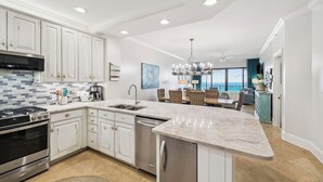 Una cocina moderna con armarios blancos, electrodomésticos de acero inoxidable, una isla grande y un comedor con vistas.