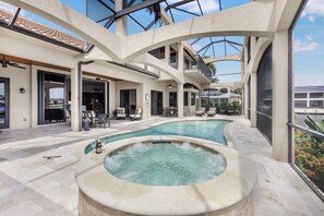 A pool area with a hot tub, outdoor seating, and a covered patio.