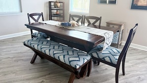 Un comedor con una mesa de madera, cojines estampados y sillas.