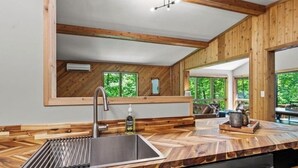 A modern kitchen with wooden accents, a large sink, and a view of the outdoors.