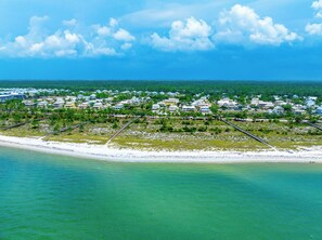 An aerial view of a coastal residential area with houses, a beach, and a clear sky.