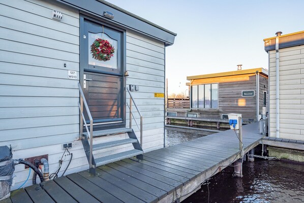 Una propiedad frente al agua con un muelle de madera que conduce a una casa con puerta principal y escalones.