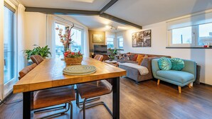 En moderne stue med et træspisebord, læderstole, en sofa og en teal farvet lænestol.