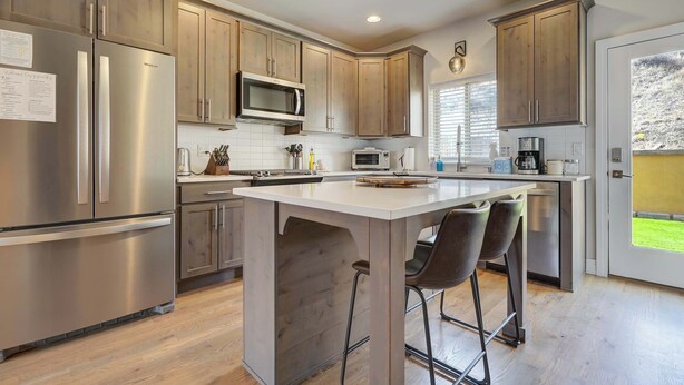 A modern kitchen with stainless steel appliances, wooden cabinets, and a central island with bar stools.