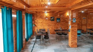 Un interior de madera con paredes de ladrillo, suelo de baldosas y un comedor con mesas y sillas.