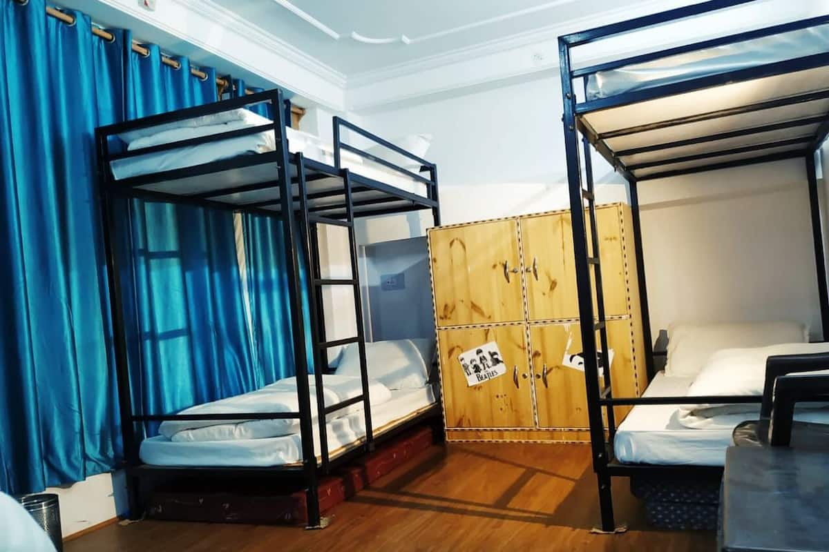 Une chambre de dortoir avec des lits superposés, une armoire en bois et un rideau.