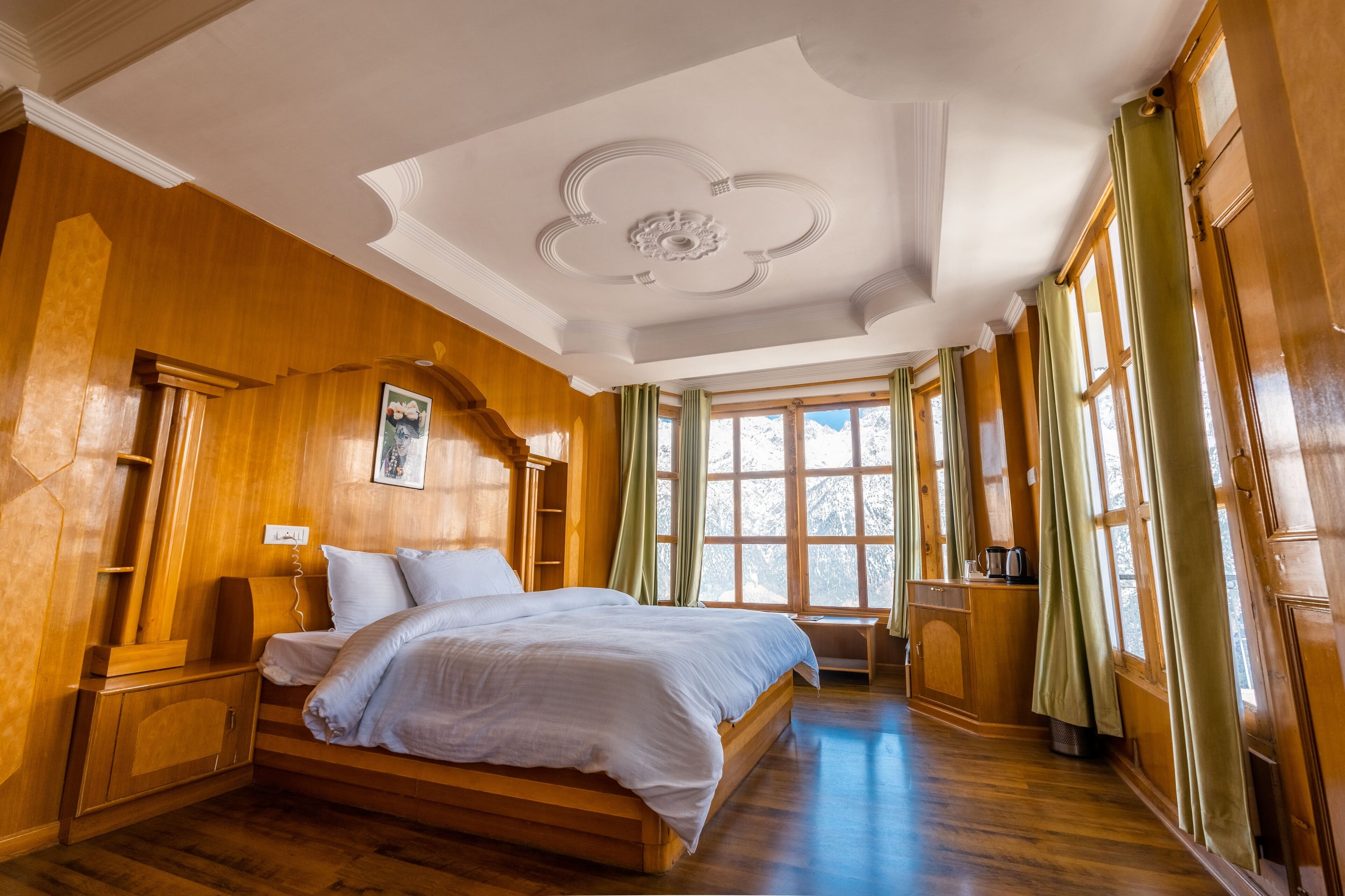 A room with a large bed, wooden walls, and a window with curtains.