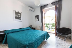 Quarto de hotel com cama, poltrona, mesa e varanda com vista.