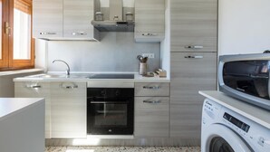 Een moderne keuken met roestvrijstalen apparatuur, een inbouwoven en een wasmachine.