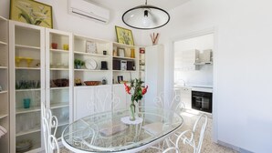 Een moderne keuken met witte kastjes, een glazen eettafel en een witte hanglamp.