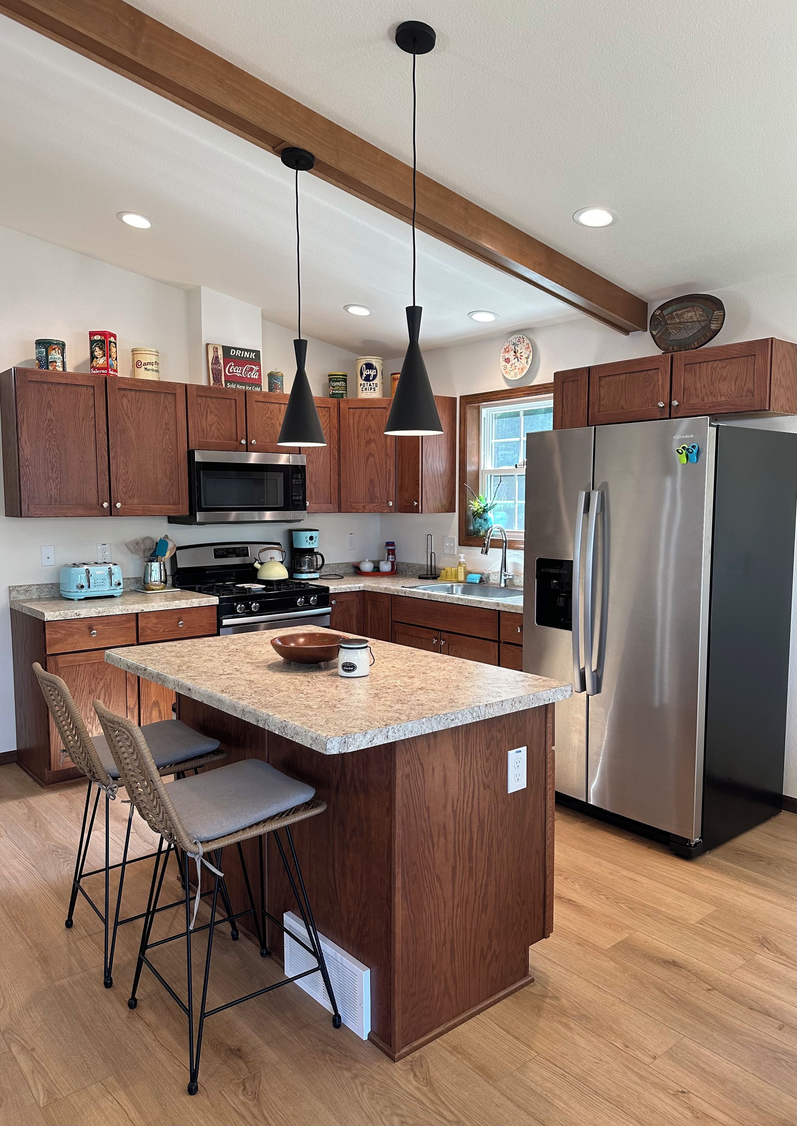 A modern kitchen with wooden cabinets, stainless steel appliances, and a central island with bar stools.