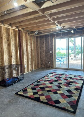 A room with exposed wooden beams, a large window, and a colorful rug. - Pointview Cottage *A/C* overlooking Crooked Lake (Manistique)