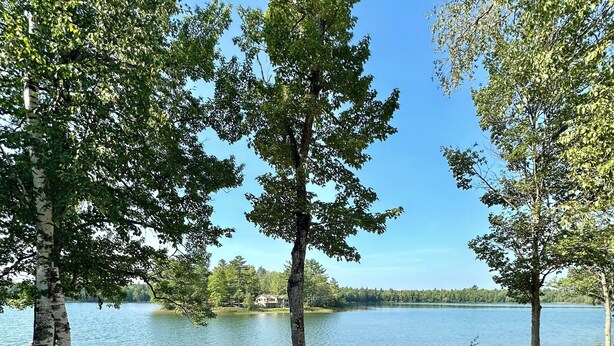 A lakeside outdoor seating area with a fire pit and white plastic chairs. - Pointview Cottage *A/C* overlooking Crooked Lake (Manistique)