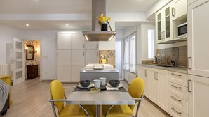 Een moderne keuken met witte kasten, een centraal eiland en gele stoelen.