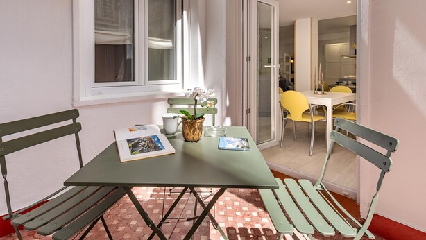 Een klein eethoekje met een tafel, stoelen, een raam en uitzicht op een keuken.