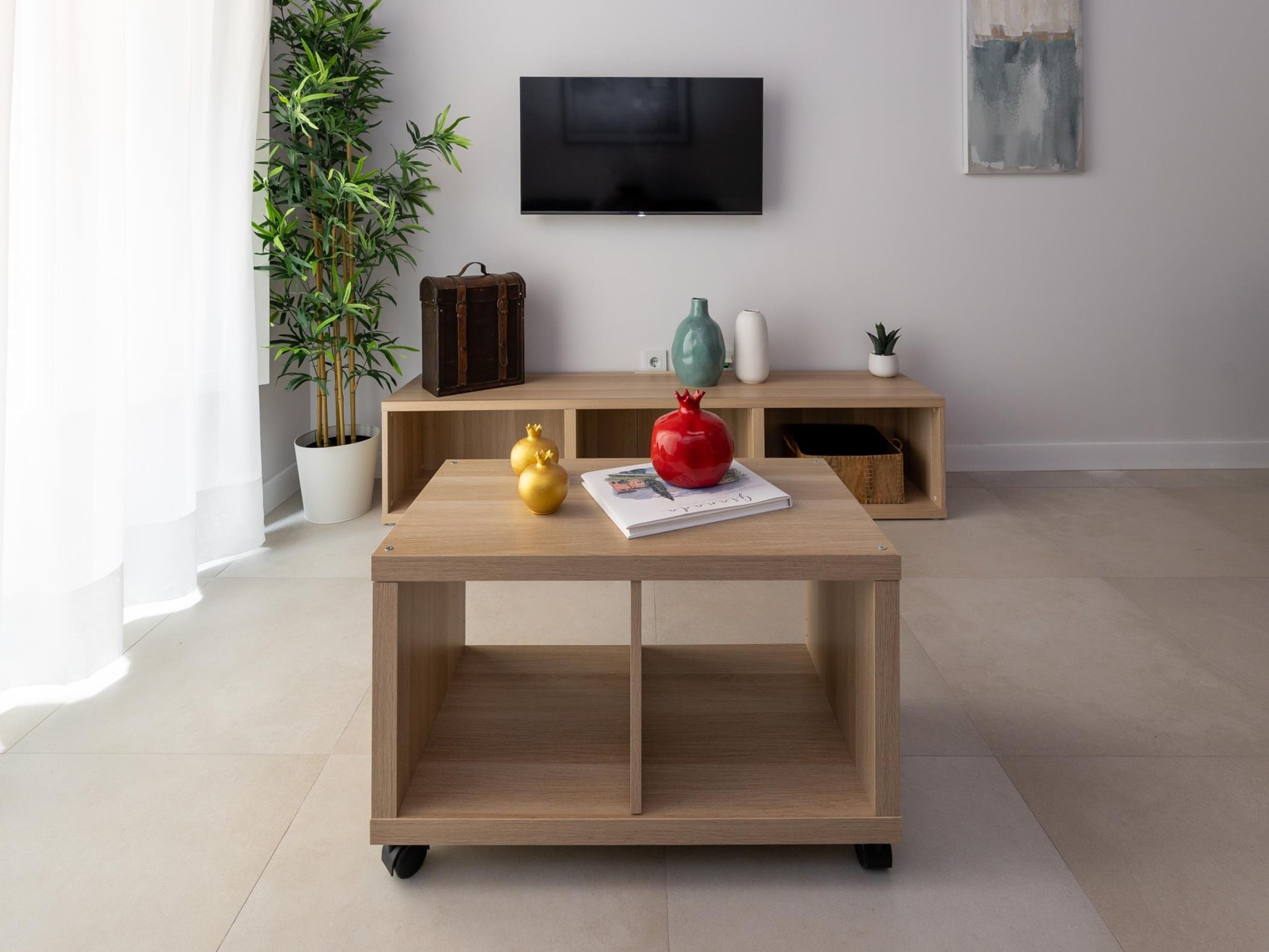 A modern living room with a wooden coffee table, a potted plant, a television, and a minimalist decor.