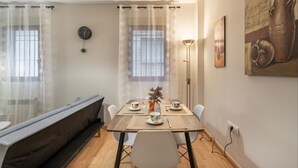 A dining area with a table set for two, a bench, and a wall clock. - Luxury Suite Campo del Pr Ncipe (Granada)