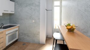 Een moderne keuken met witte kastjes, een ingebouwde oven en een marmeren achterwand.