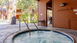 Ein Bereich mit Whirlpool, Holzterrasse, Liegestuhl und einem Schild mit den Spa-Öffnungszeiten.