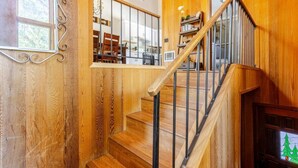 Eine Holztreppe mit Metallgeländer, die zu einer erhöhten Ebene mit Esstisch und Stühlen führt.