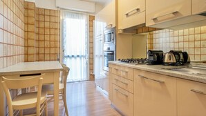 Une cuisine moderne avec un coin repas, comprenant un îlot de cuisine, une cuisinière, un four et un four à micro-ondes.