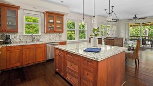 A spacious kitchen with wooden cabinets, a marble countertop, and a large island. - Pili Mai at Poipu 15b By Parrish Kauai - spacious condo great for families! (Koloa)