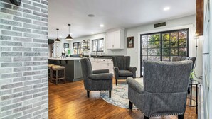 A modern kitchen with white cabinets, a large window, and a bar area. - Andover in-town, upscale furnished home, single level living & 2-car garage (Andover)