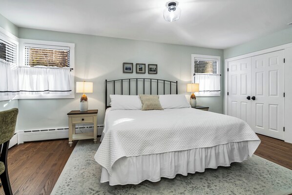 A bedroom with a large bed, two bedside tables with lamps, a chair, and a wardrobe.