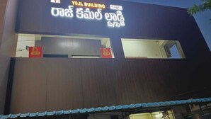 A building with a sign reading "YSJL BUILDING" and another sign in a local language. - Raj Kamal Lodge (Chirala)